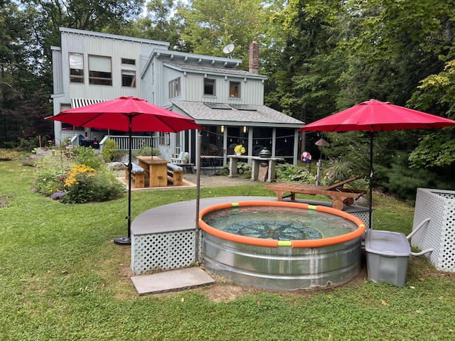 rear view of house featuring a lawn and a jacuzzi