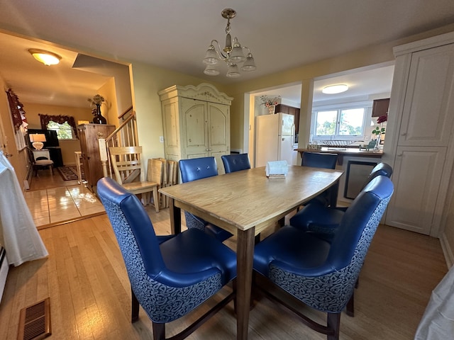 dining room with light wood-type flooring and a notable chandelier