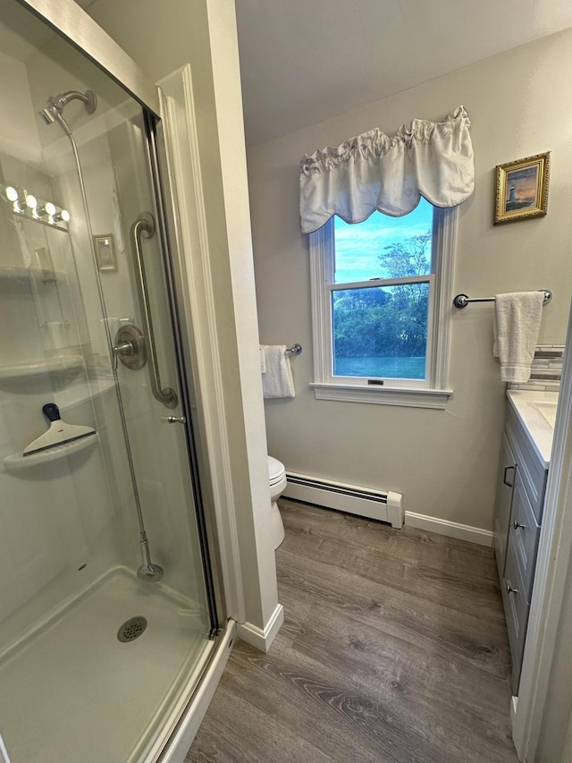 bathroom featuring vanity, an enclosed shower, toilet, hardwood / wood-style flooring, and baseboard heating