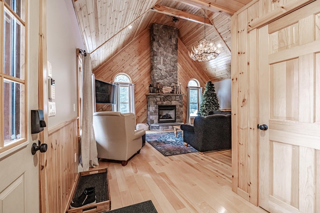 living area featuring a chandelier, light wood-style floors, wood ceiling, wooden walls, and high vaulted ceiling