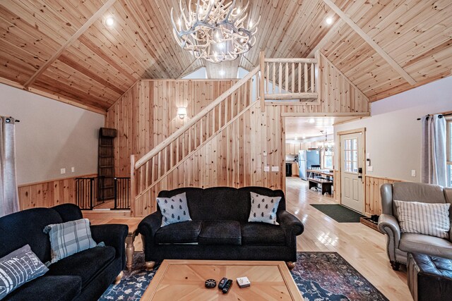 living room featuring high vaulted ceiling, wooden walls, hardwood / wood-style floors, wooden ceiling, and an inviting chandelier