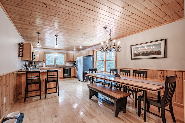 dining space with light hardwood / wood-style flooring, wooden walls, wooden ceiling, and a wealth of natural light