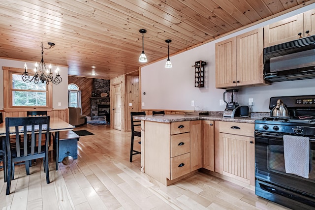 kitchen with wood walls, black appliances, a chandelier, and light brown cabinets