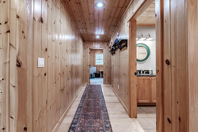 hallway featuring wooden walls, sink, light hardwood / wood-style floors, and wooden ceiling