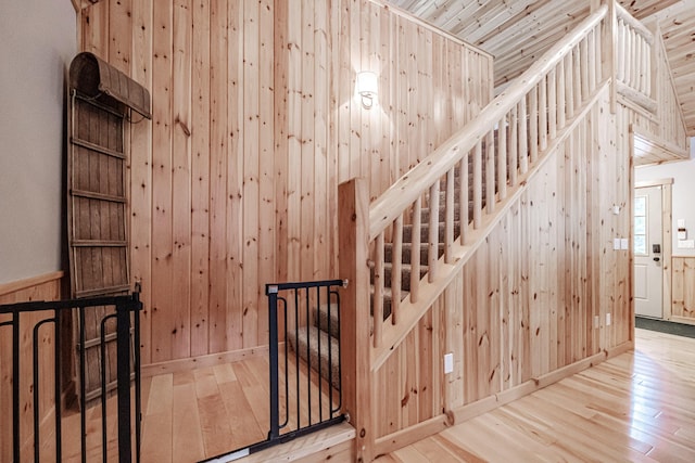 stairs featuring hardwood / wood-style floors, wooden walls, and baseboards