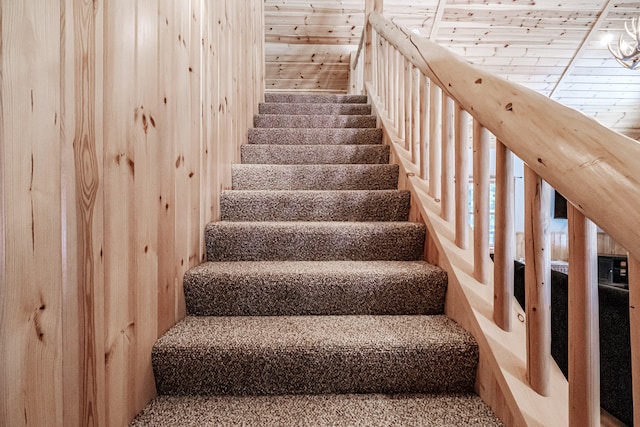 stairway featuring wood walls and wooden ceiling