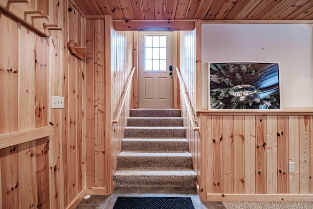 stairway featuring wood ceiling and wood walls