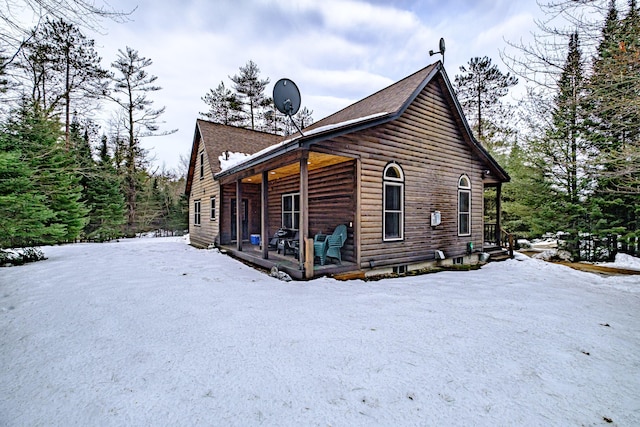 snow covered property featuring log veneer siding