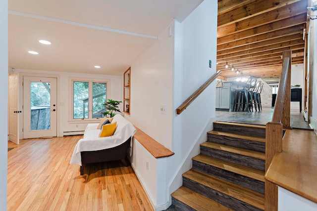 stairway with a baseboard heating unit and hardwood / wood-style floors