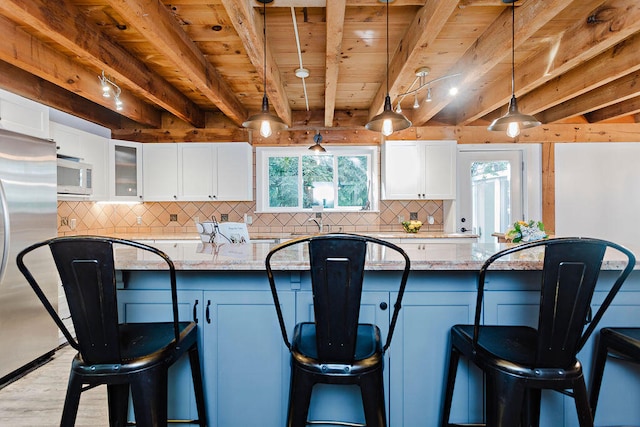 kitchen with light stone counters, white cabinetry, appliances with stainless steel finishes, and hanging light fixtures