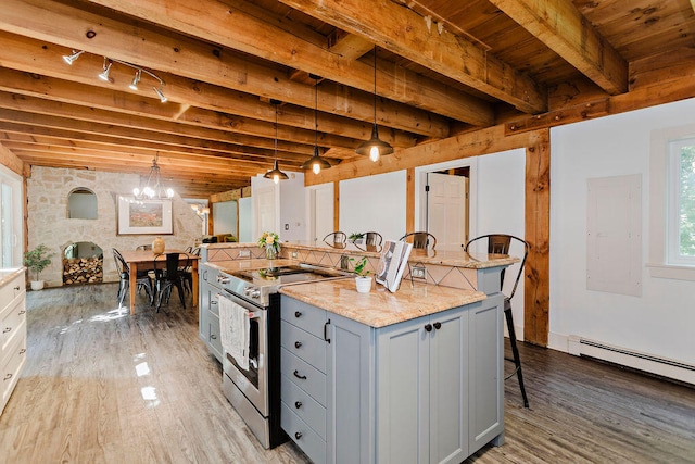 kitchen with stainless steel electric range, a breakfast bar, a center island, light stone countertops, and decorative light fixtures