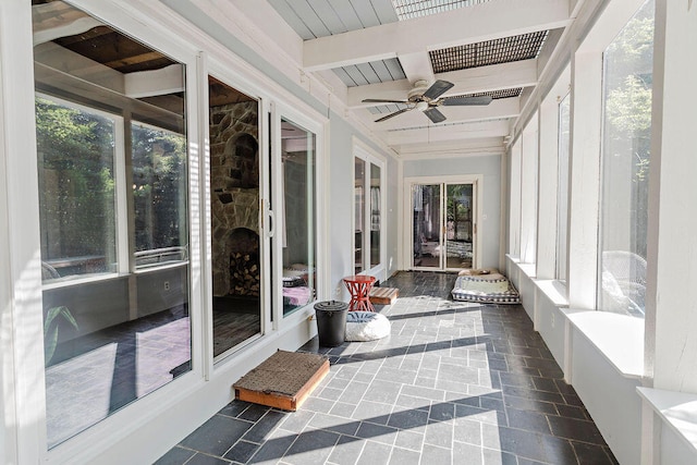 sunroom with ceiling fan and beamed ceiling