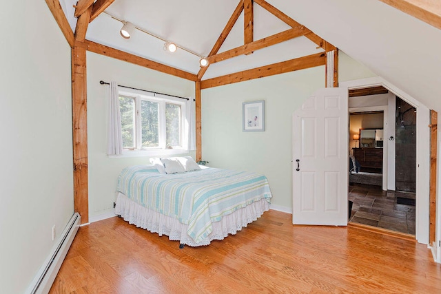 bedroom with lofted ceiling, hardwood / wood-style floors, and baseboard heating