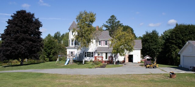 view of front of home with a playground, an outdoor structure, a front yard, and a garage