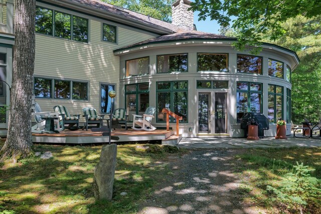 rear view of house featuring a sunroom and a deck