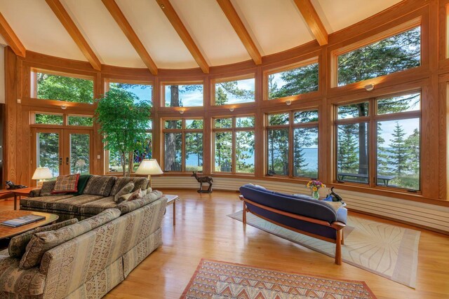 living room featuring high vaulted ceiling, light hardwood / wood-style floors, and french doors