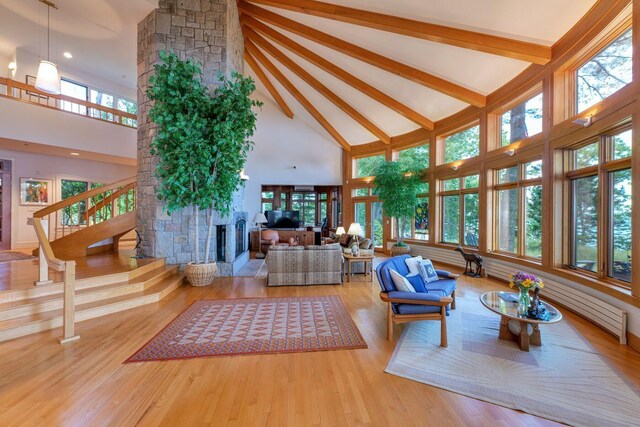 living room with a fireplace, high vaulted ceiling, hardwood / wood-style floors, and beam ceiling