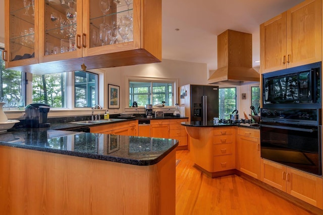 kitchen with black appliances, light hardwood / wood-style floors, kitchen peninsula, sink, and dark stone counters