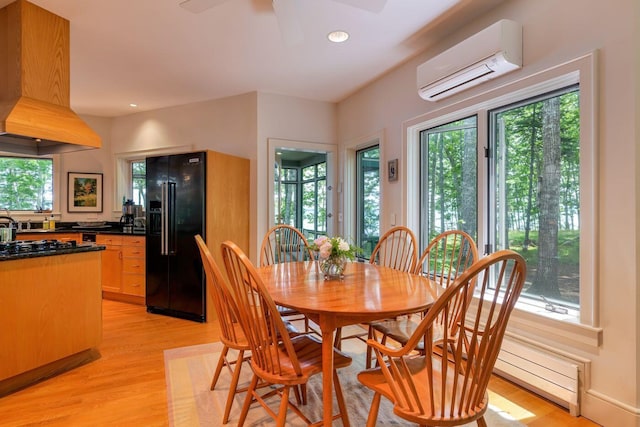 dining room with ceiling fan, an AC wall unit, and light wood-type flooring