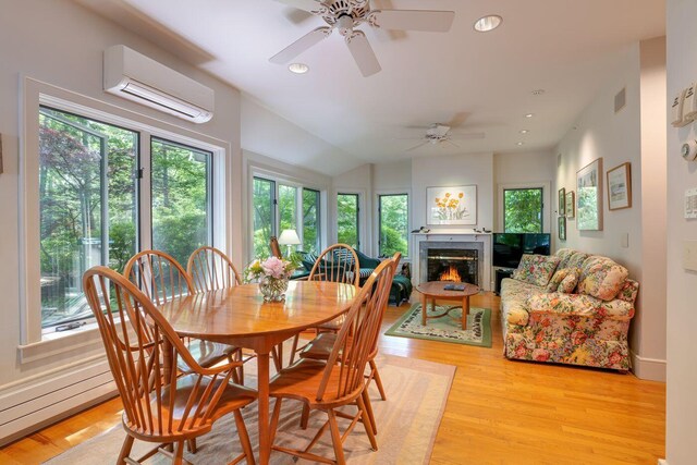 dining room featuring ceiling fan, a wall unit AC, and light hardwood / wood-style floors