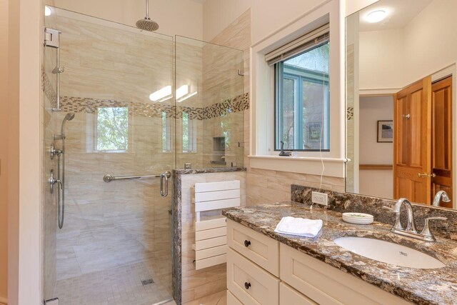 bathroom featuring a shower with door and vanity