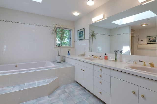 bathroom featuring tile patterned flooring, tiled bath, vanity, and a skylight