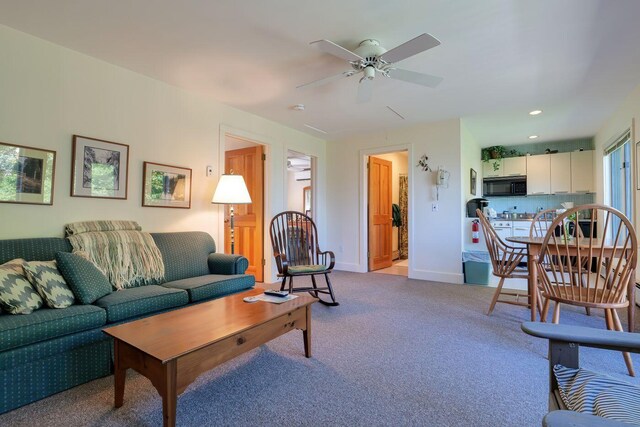 carpeted living room with ceiling fan