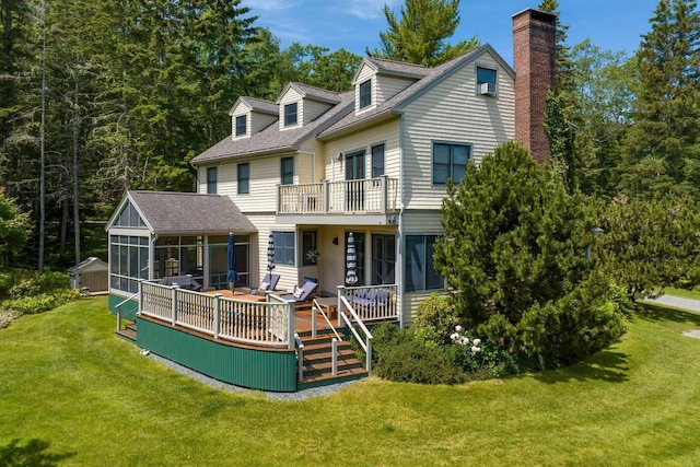 rear view of house with a wooden deck, a yard, and a sunroom