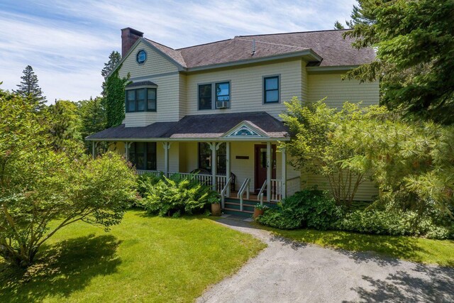 view of front of home featuring cooling unit, covered porch, and a front yard