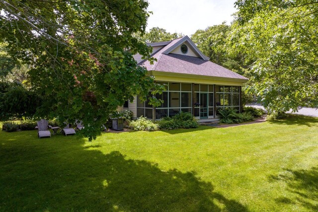 rear view of property featuring a lawn and a sunroom