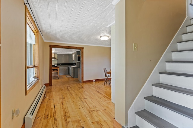 stairway with ornamental molding, hardwood / wood-style flooring, and a baseboard radiator