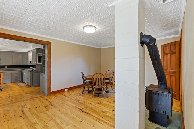 dining space featuring sink, light hardwood / wood-style floors, and ornamental molding