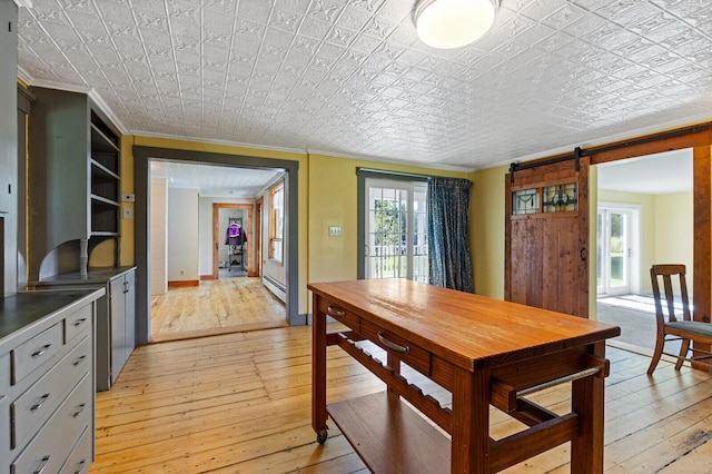 dining area with ornamental molding, light hardwood / wood-style flooring, a barn door, and a baseboard radiator