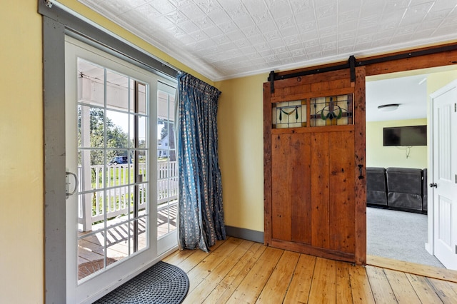 doorway featuring light wood-type flooring, ornamental molding, and a barn door