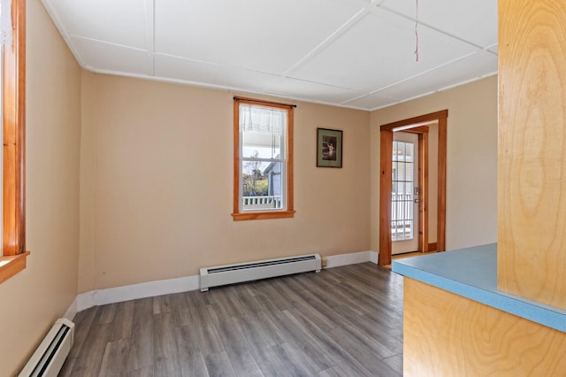 empty room featuring a baseboard heating unit, plenty of natural light, and hardwood / wood-style floors