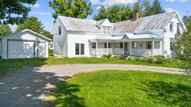 view of front facade with covered porch, an outbuilding, a garage, and a front lawn