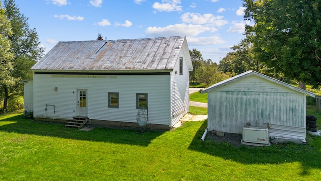 rear view of property with an outdoor structure and a yard