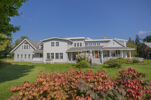 rear view of house featuring a lawn and covered porch