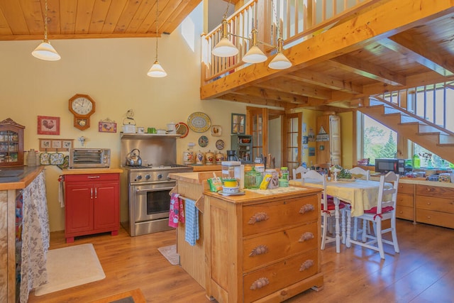 kitchen with light wood-type flooring, wood ceiling, stainless steel range, wooden counters, and pendant lighting