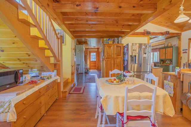 dining area featuring vaulted ceiling with beams and light hardwood / wood-style floors