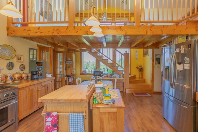 kitchen featuring beamed ceiling, appliances with stainless steel finishes, butcher block countertops, and light hardwood / wood-style floors