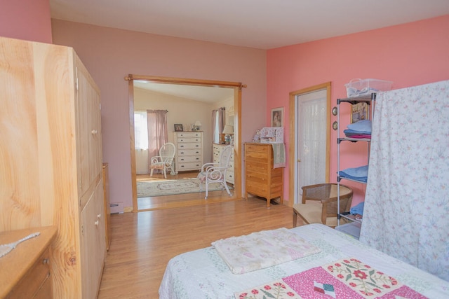 bedroom featuring a baseboard heating unit, vaulted ceiling, and light hardwood / wood-style flooring