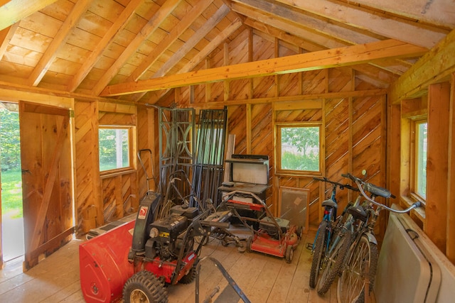 miscellaneous room featuring lofted ceiling, plenty of natural light, hardwood / wood-style floors, and wooden walls