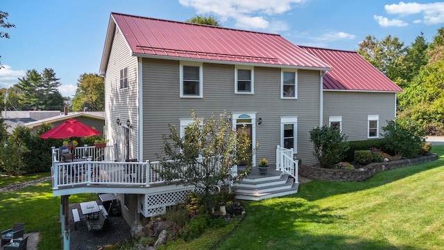 back of property featuring a wooden deck and a lawn