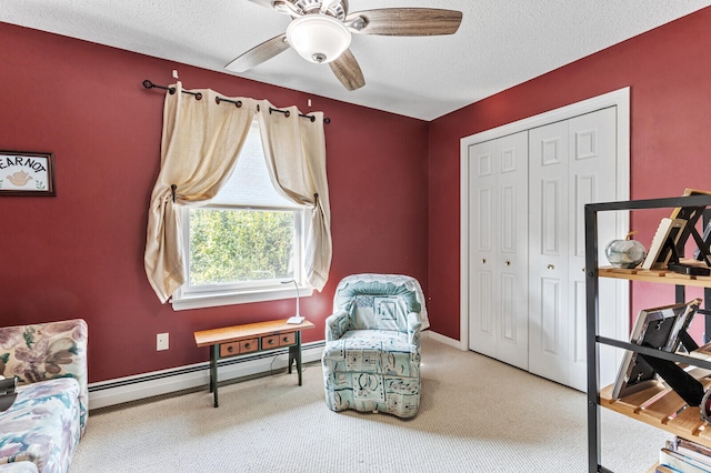 sitting room with carpet flooring, ceiling fan, baseboard heating, and a textured ceiling