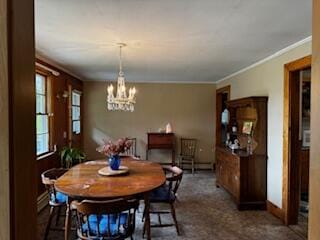 dining area featuring dark carpet, a chandelier, and crown molding