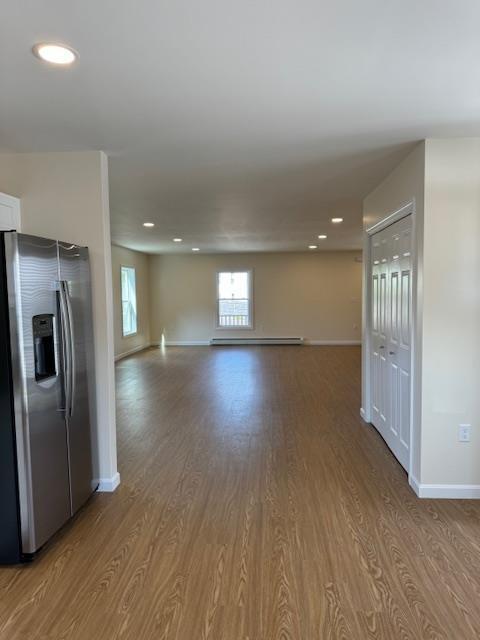 kitchen featuring white cabinetry, hardwood / wood-style flooring, a baseboard radiator, and stainless steel fridge with ice dispenser