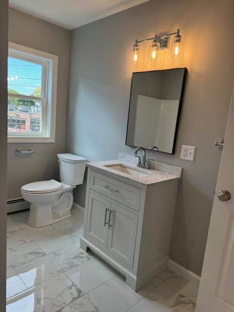 bathroom featuring a baseboard heating unit, toilet, and vanity