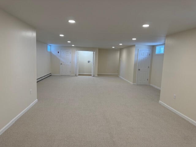 basement with a baseboard radiator and light colored carpet