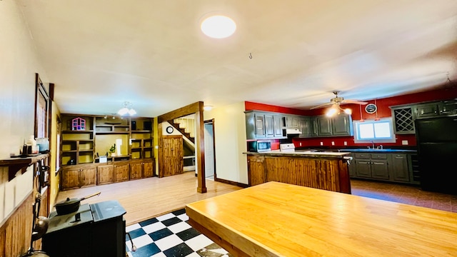 kitchen featuring kitchen peninsula, black refrigerator, white stove, ceiling fan, and sink